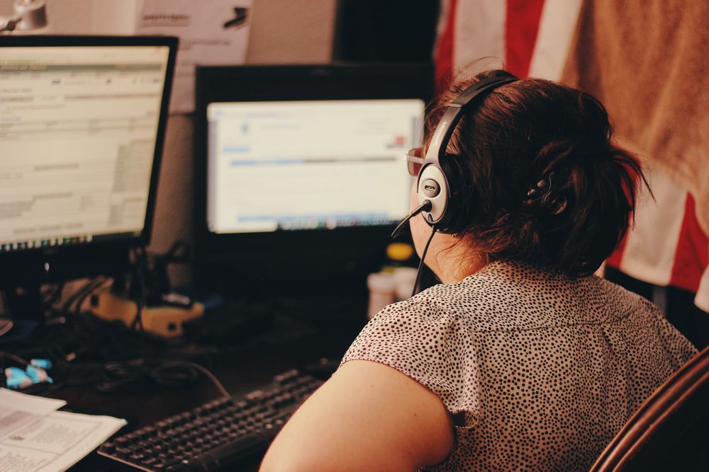 Dispatcher wearing a headset working across two monitors